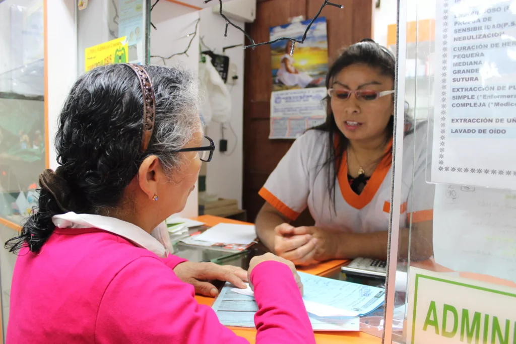 Carmen, técnica en enfermería atiende en farmacia a una adulta mayor.